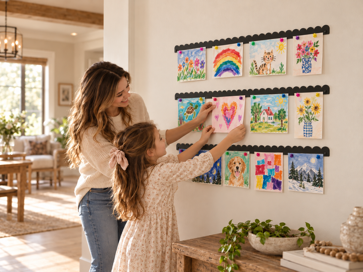 Kids art gallery wall made with three black scalloped magnetic art displays, mother and daughter hanging artwork