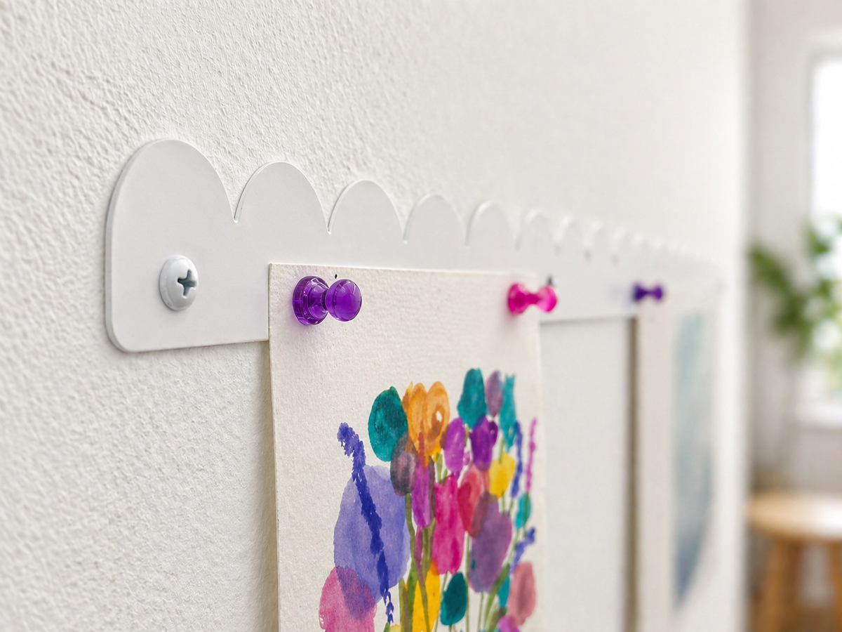 Close up side view of a white scalloped magnetic art bar sitting flush against the wall