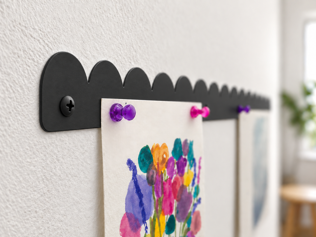 Close up side view of a black scalloped magnetic art bar holding a watercolor painting